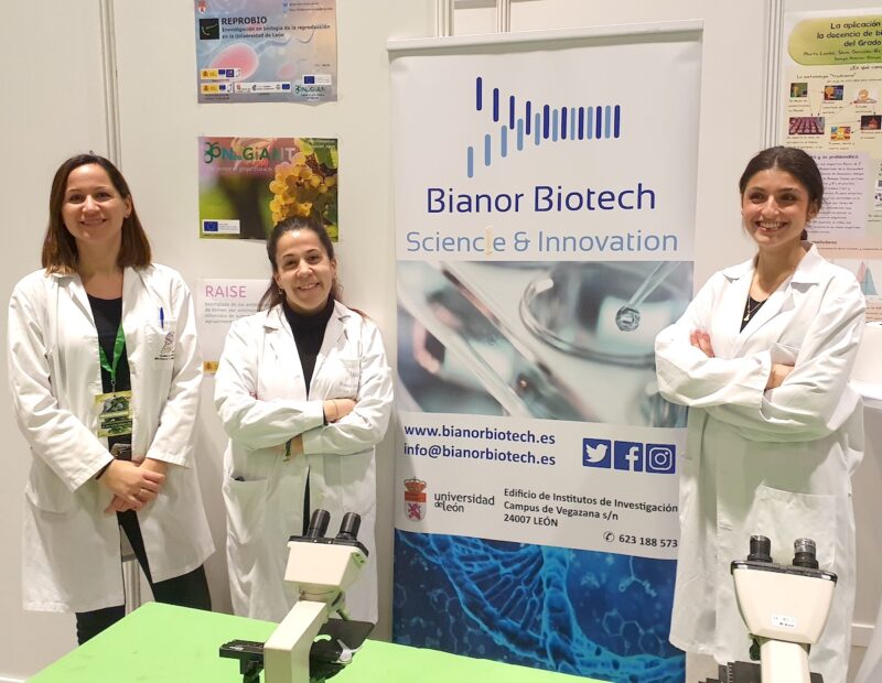 Estela, Estíbaliz y Cristina junto con el roll-on de Bianor. Las tres visten bata de laboratorio.
